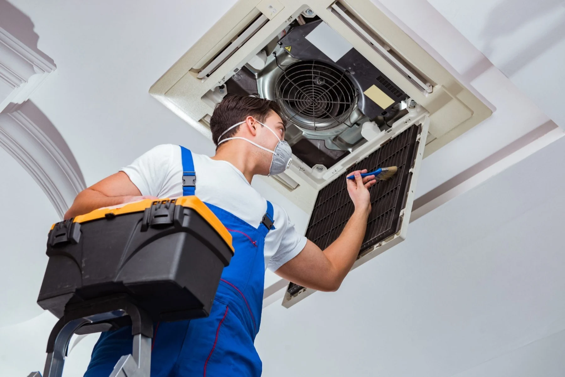 HVAC technician servicing a ceiling-mounted air-conditioning system