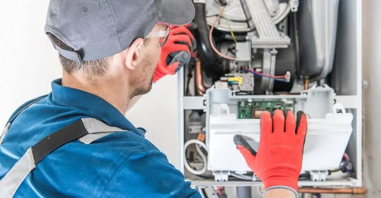 Technician working on the internal components of a heating unit